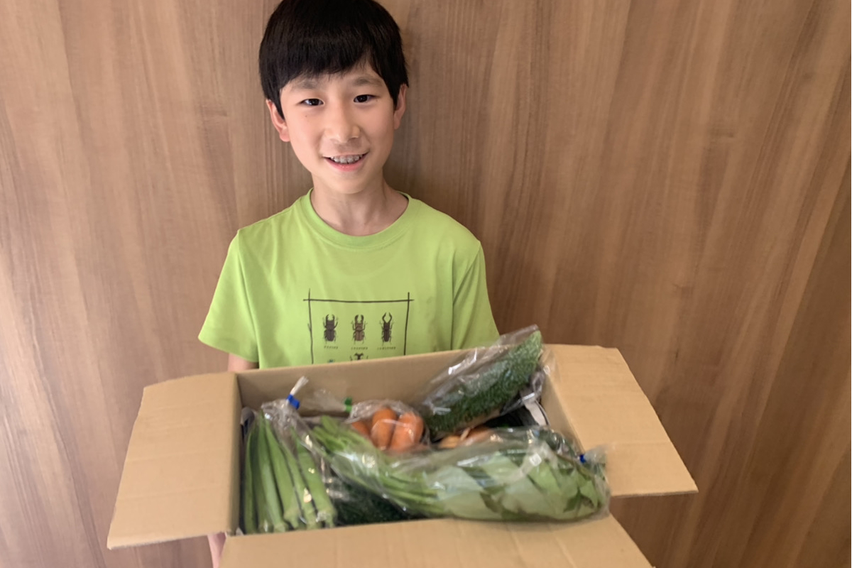おまかせ野菜BOXを抱える少年の画像